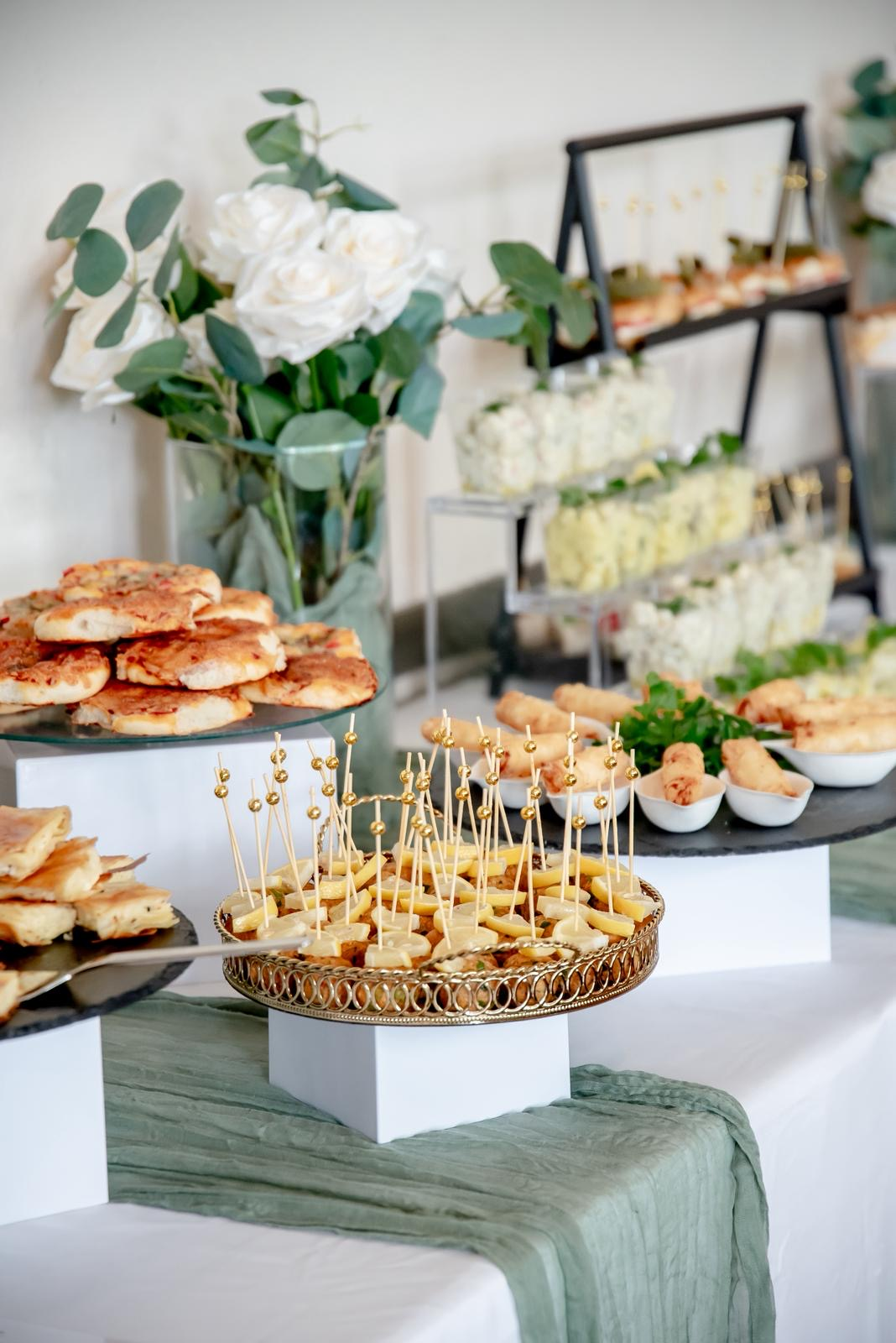 Herzhafte Catering-Spezialitäten von Mery's Catering Stuttgart: Käse-Spieße auf goldenem Tablett, Börek und gebackenes Fingerfood mit weißen Rosen und Eukalyptus-Dekoration